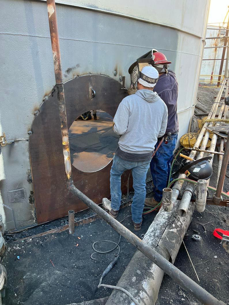Two men are working on a large metal structure.