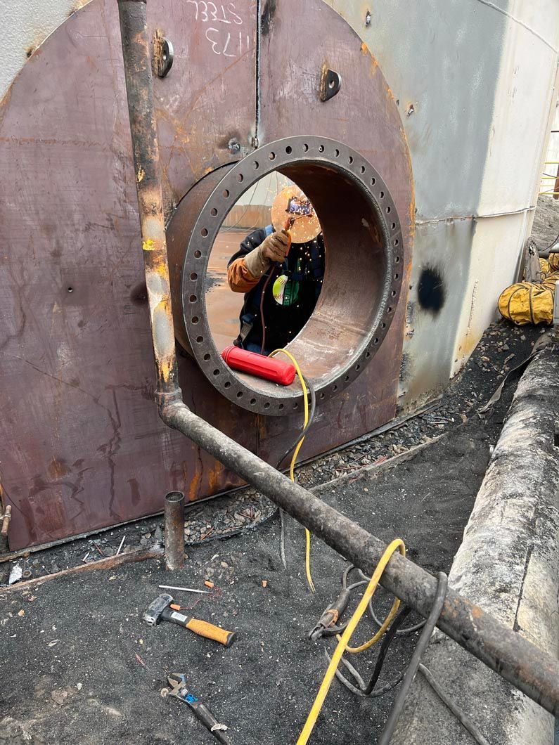 A man is sitting in a hole in a pipe.