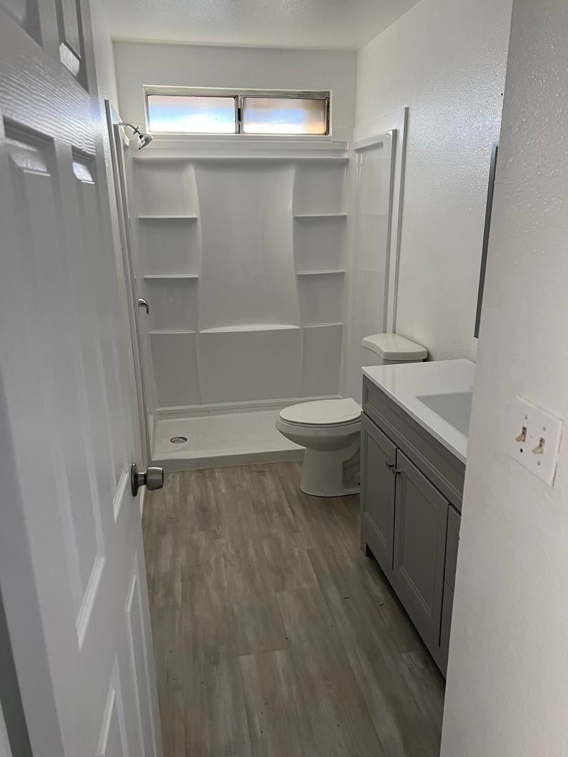 A bathroom with a toilet , sink , shower and window.