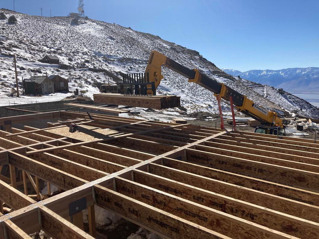 A crane is lifting a large piece of wood on top of a wooden structure.