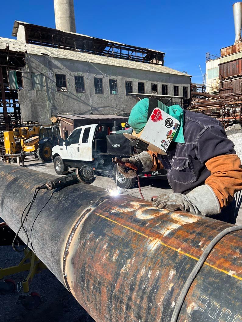 A man is welding a pipe in front of a building.