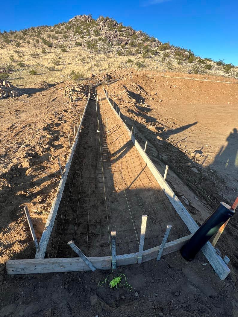 A fence is being built in the desert with a mountain in the background.