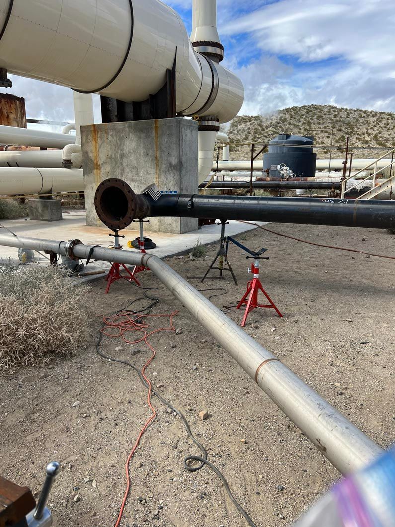 A bunch of pipes are sitting on top of a dirt field.