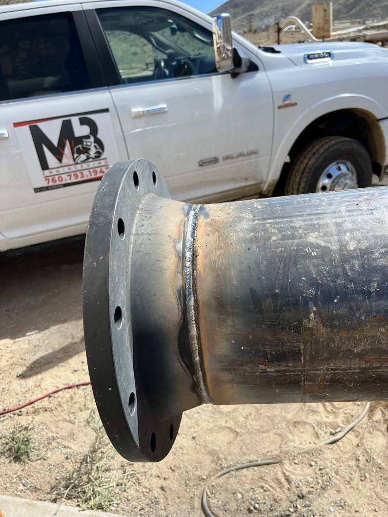 A white truck is parked next to a metal pipe.
