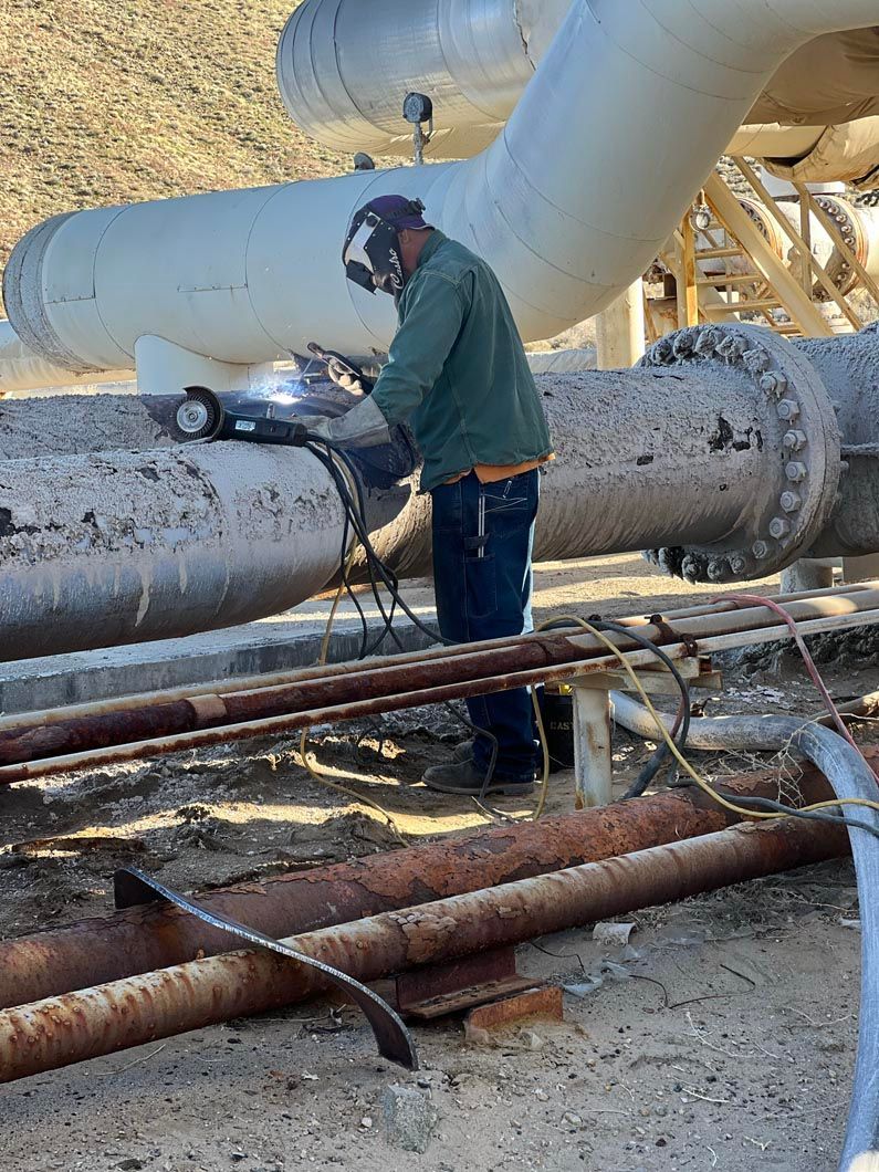 A man is welding a pipe in a factory.