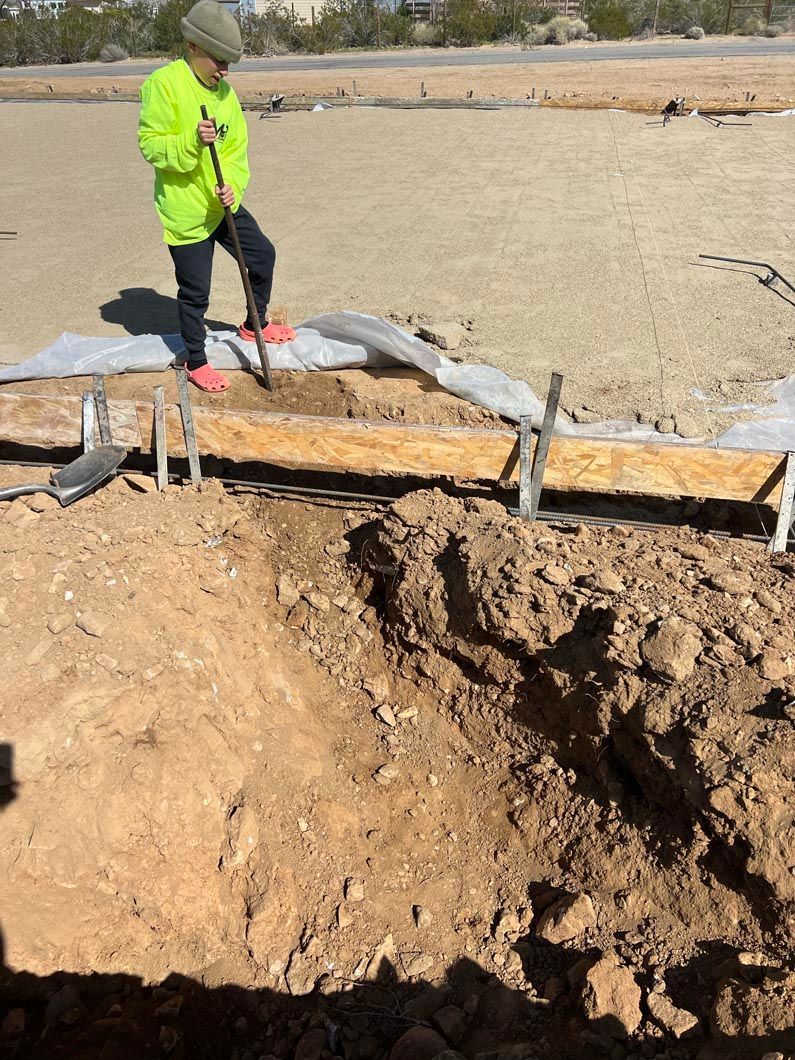 A man is standing on top of a pile of dirt holding a shovel.