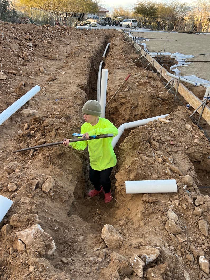A little boy is digging a hole in the dirt with a shovel.