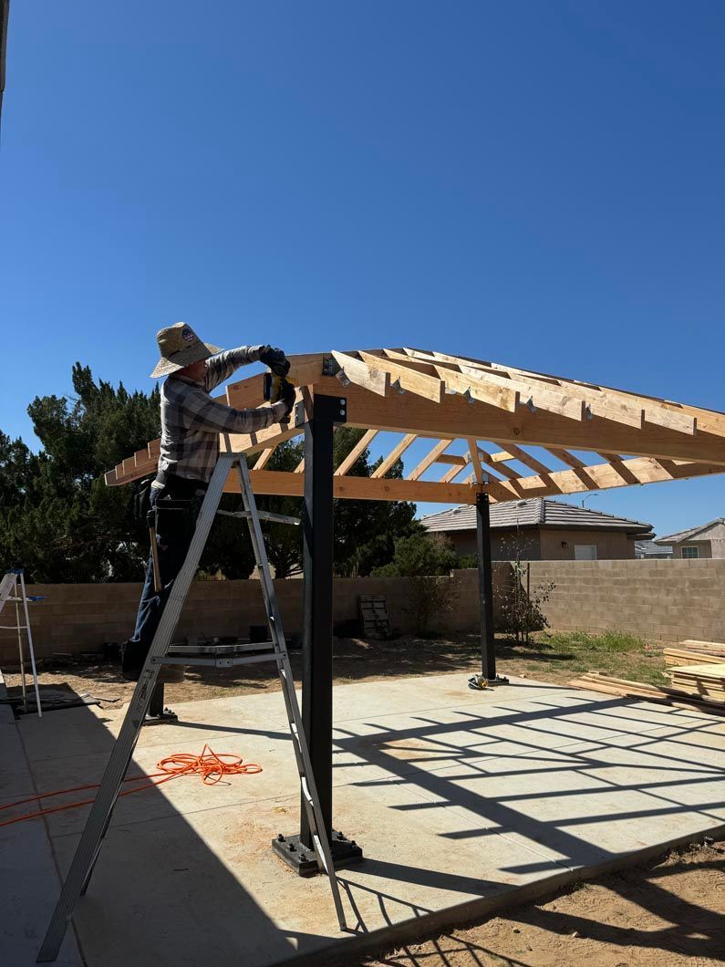 A man is standing on a ladder working on a wooden structure.