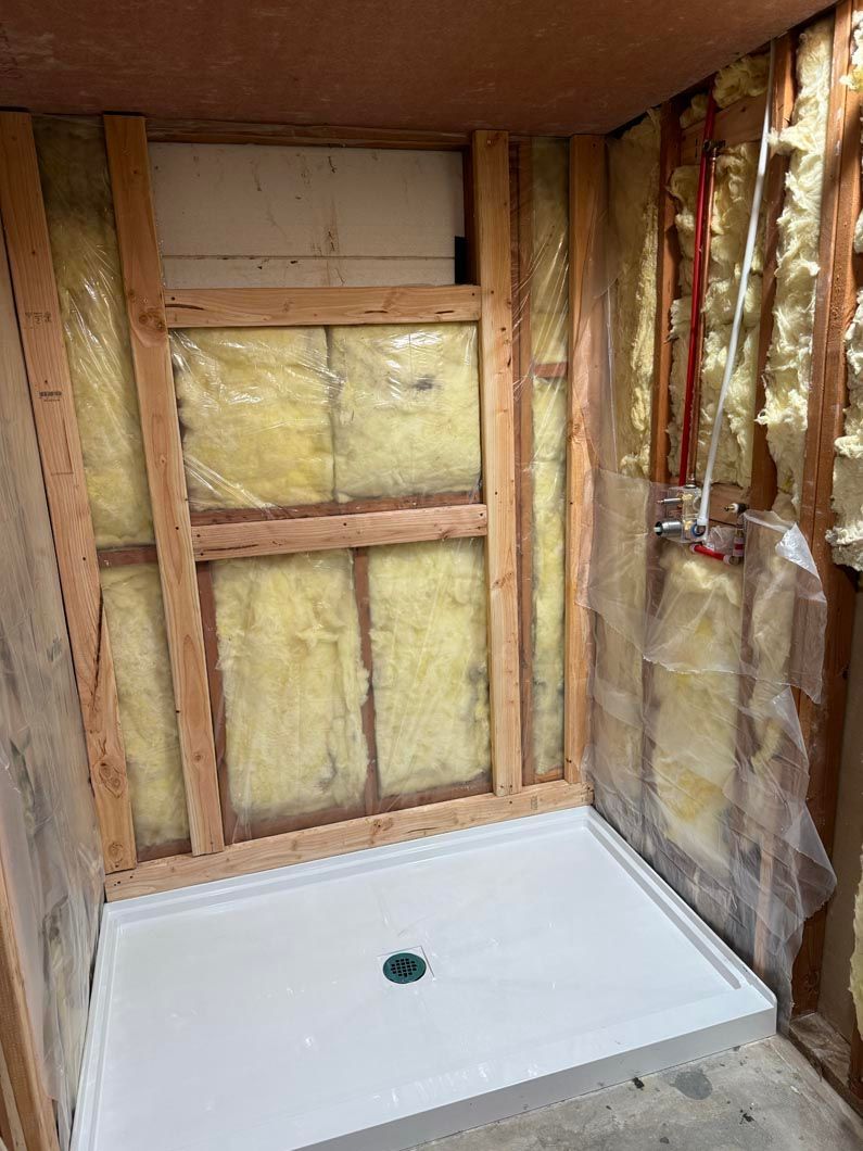 A shower stall is being installed in a bathroom under construction.