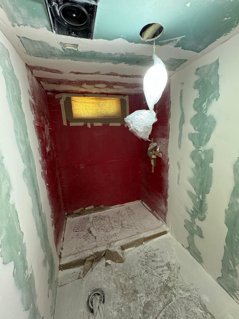 A bathroom under construction with a red wall and a window.