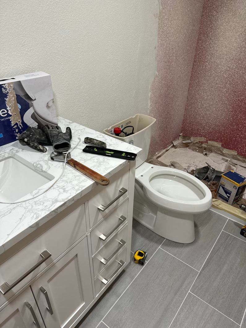 A bathroom with a toilet , sink , and measuring tape on the floor.