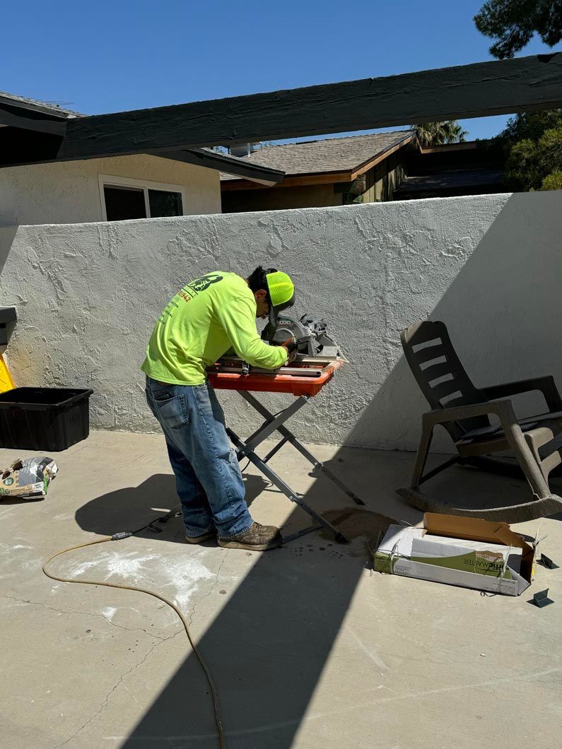 A man in a neon green shirt is working on a table saw.