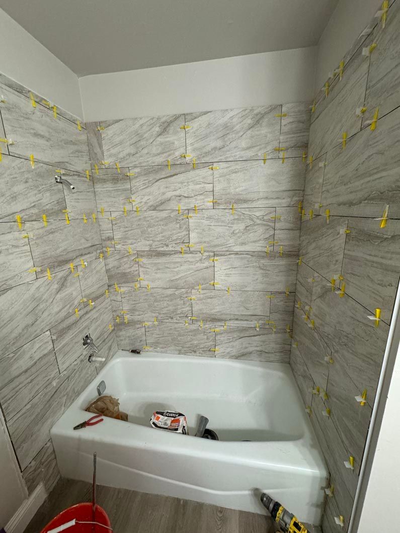 A bathroom with a bathtub and a tiled wall.