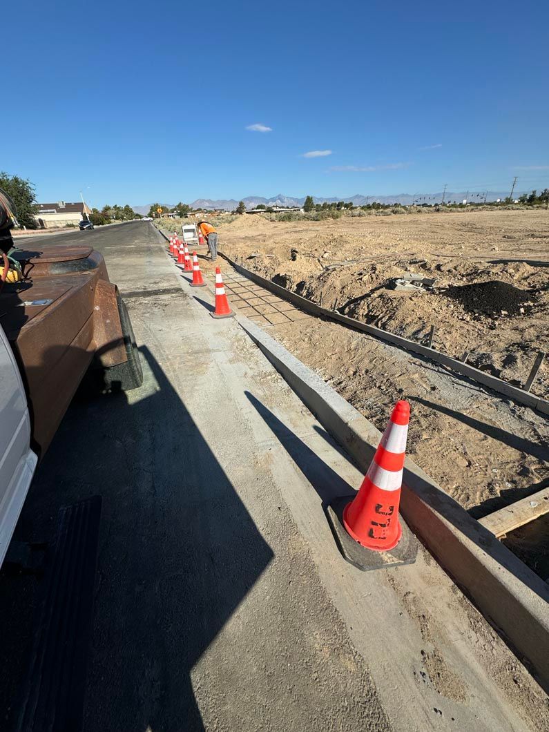 A row of orange and white traffic cones are sitting on the side of a road.