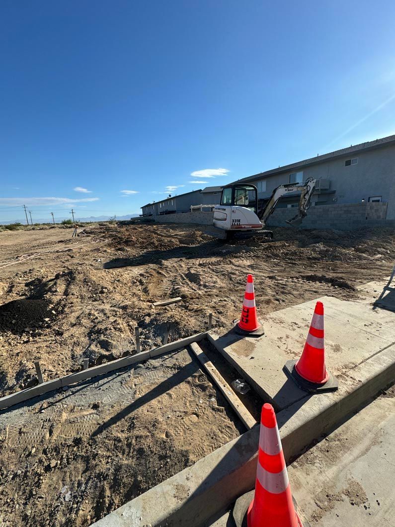 A construction site with orange cones and a bulldozer in the background.