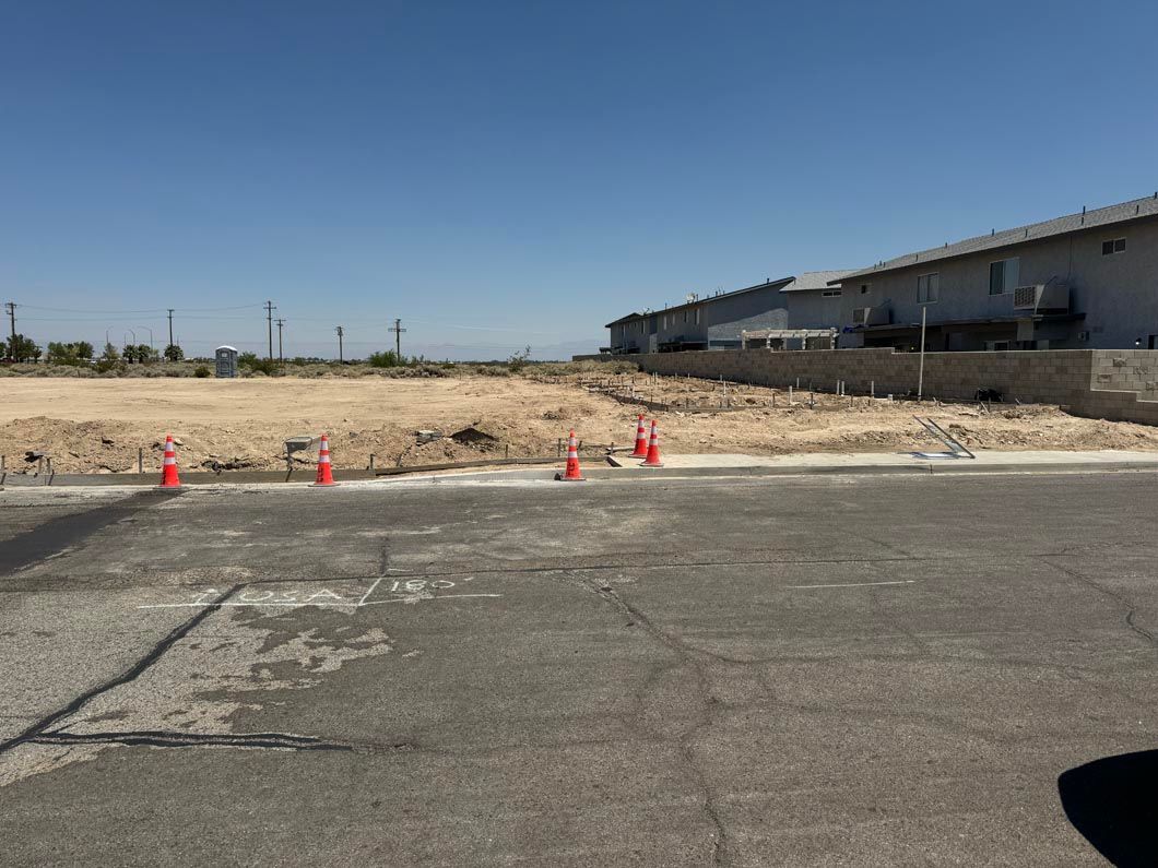 A parking lot with red cones and a building in the background.