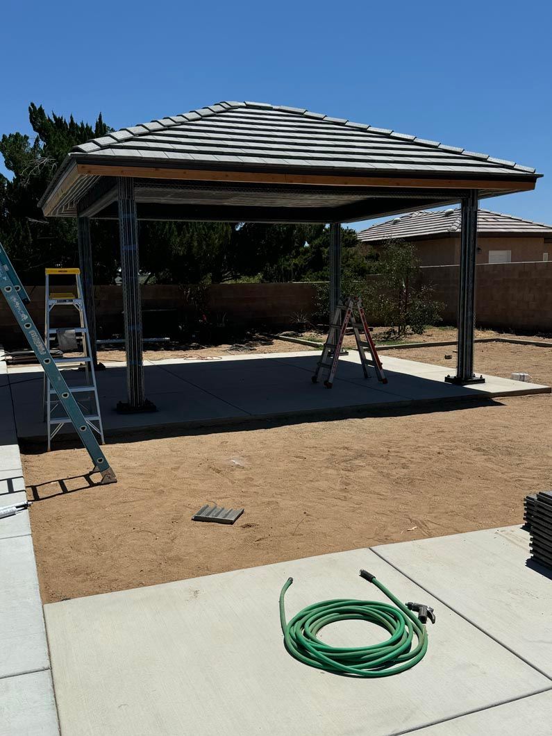 A green hose is laying on the ground next to a ladder