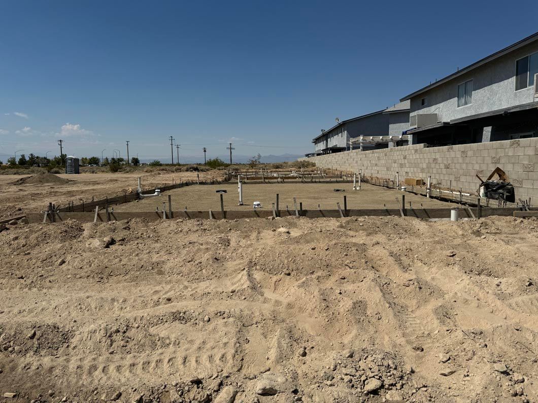 A construction site with a lot of dirt and a building in the background.