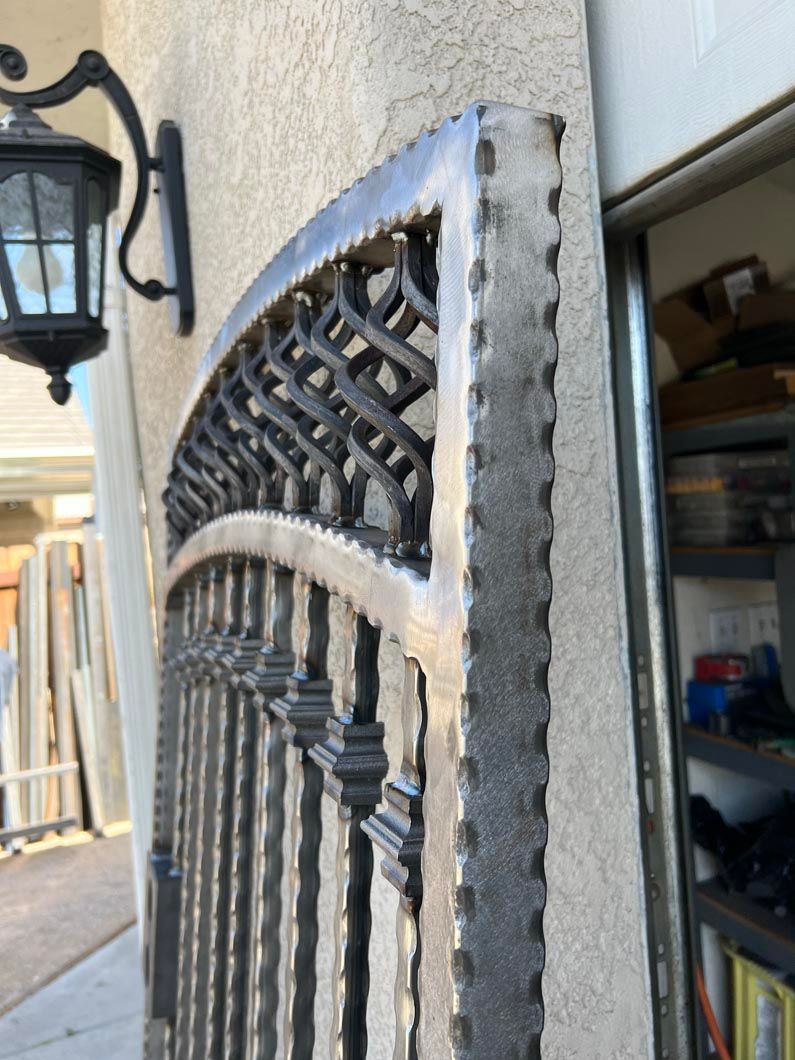 A wrought iron gate is on the side of a building