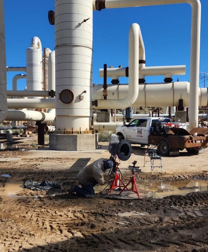 A man is working on a pipe in a field