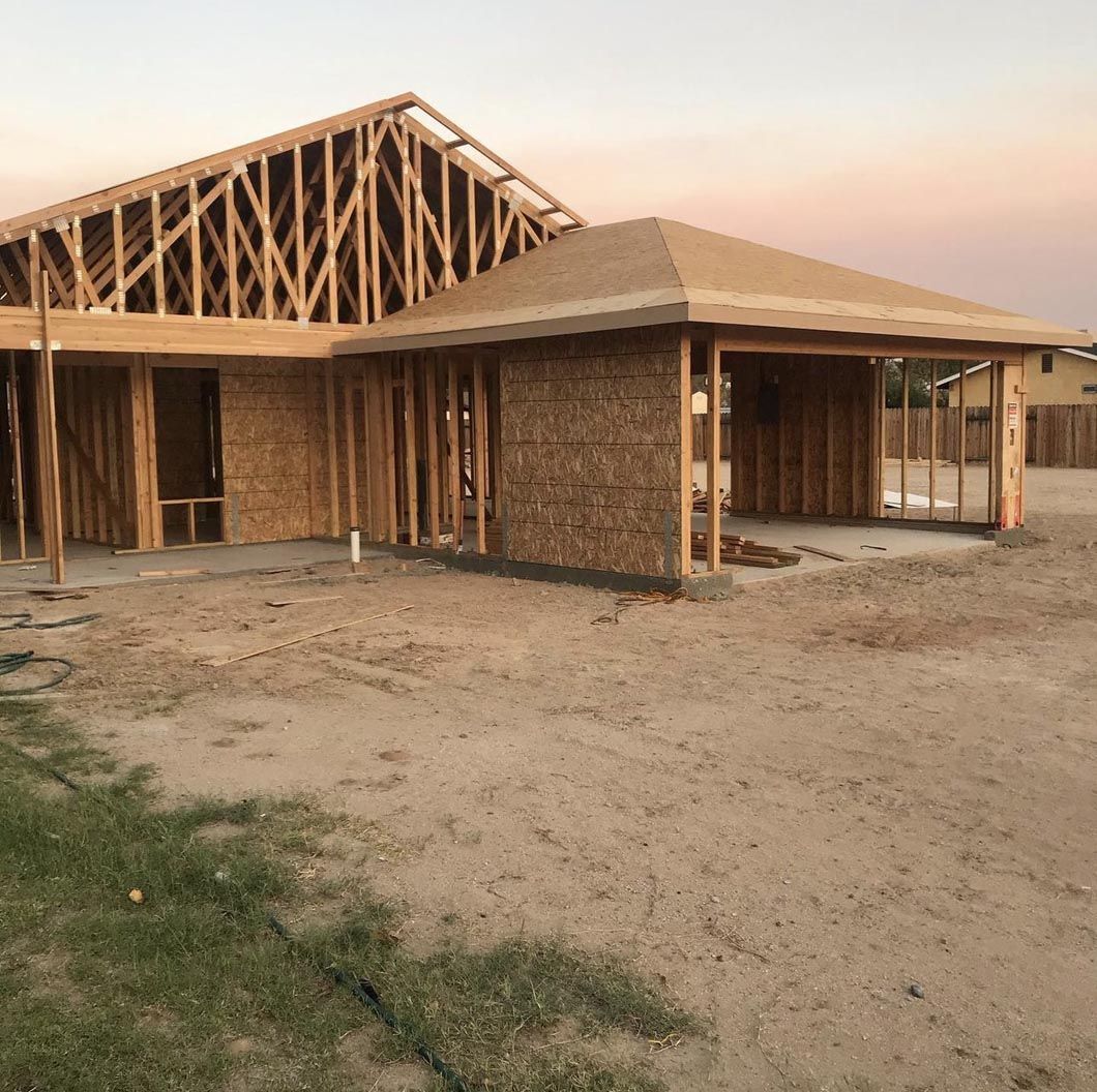 A house is being built in the middle of a dirt field.