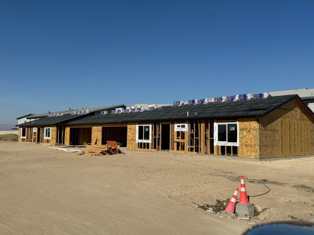 A building is being built in the middle of a dirt field.