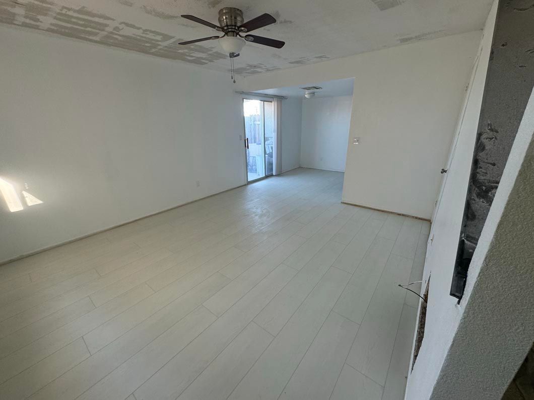 An empty room with a ceiling fan and a sliding glass door.