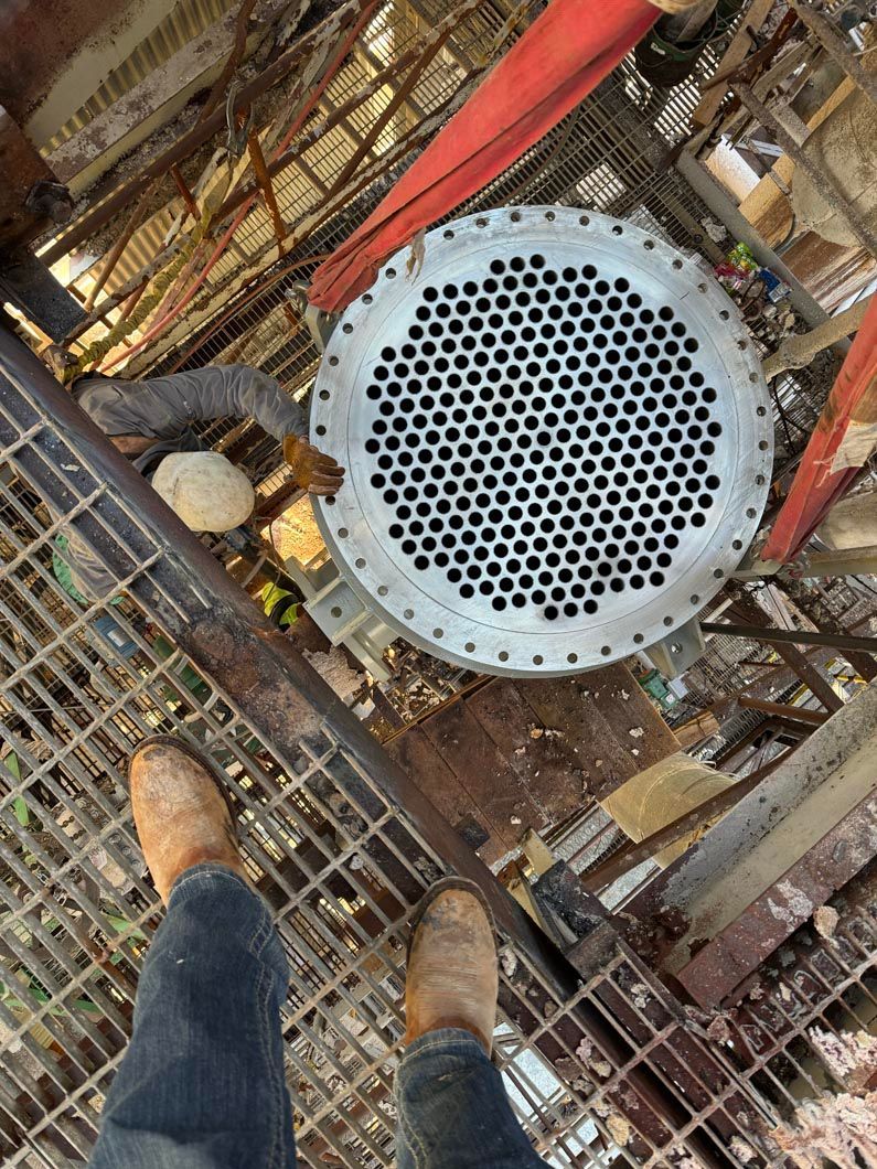 A person is standing next to a large metal pipe.