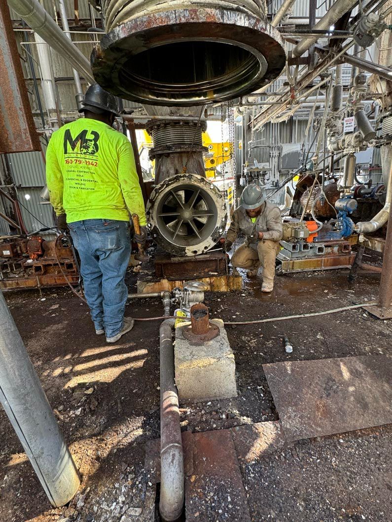 Two men are working on a large machine in a factory.
