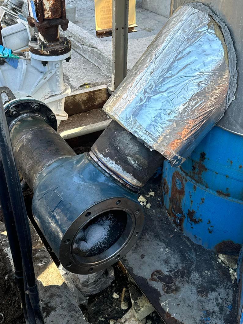 A close up of a metal pipe sitting on top of a concrete surface.