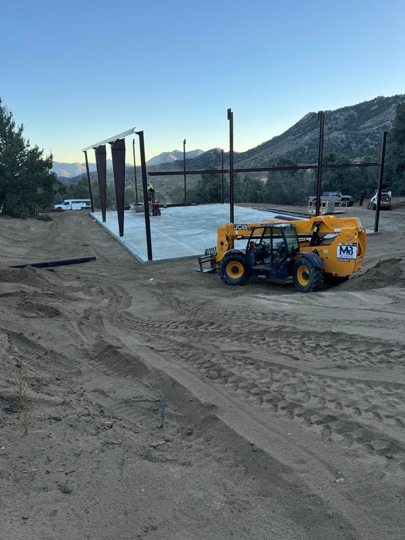 A yellow forklift is sitting on top of a dirt field.