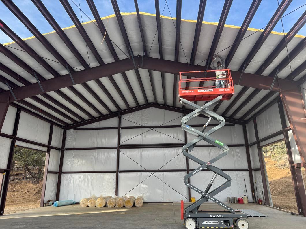 A man is standing on a scissor lift in a large building.