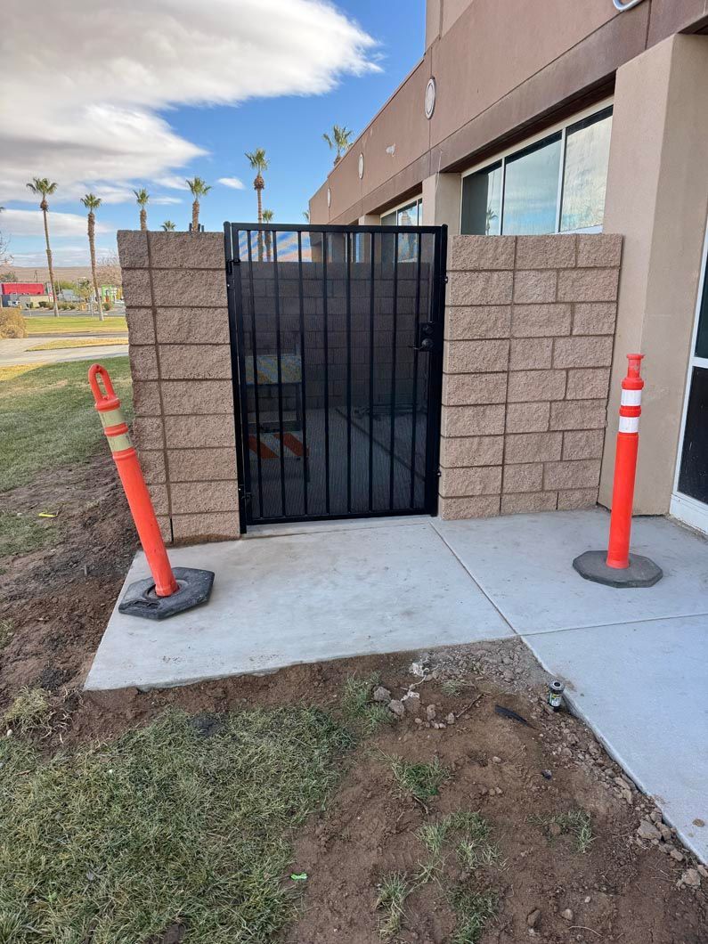 A brick wall with a gate and orange cones in front of it.