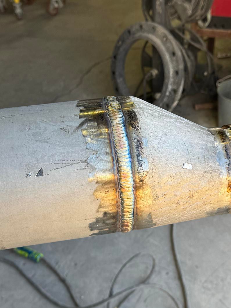 A close up of a stainless steel pipe being welding.