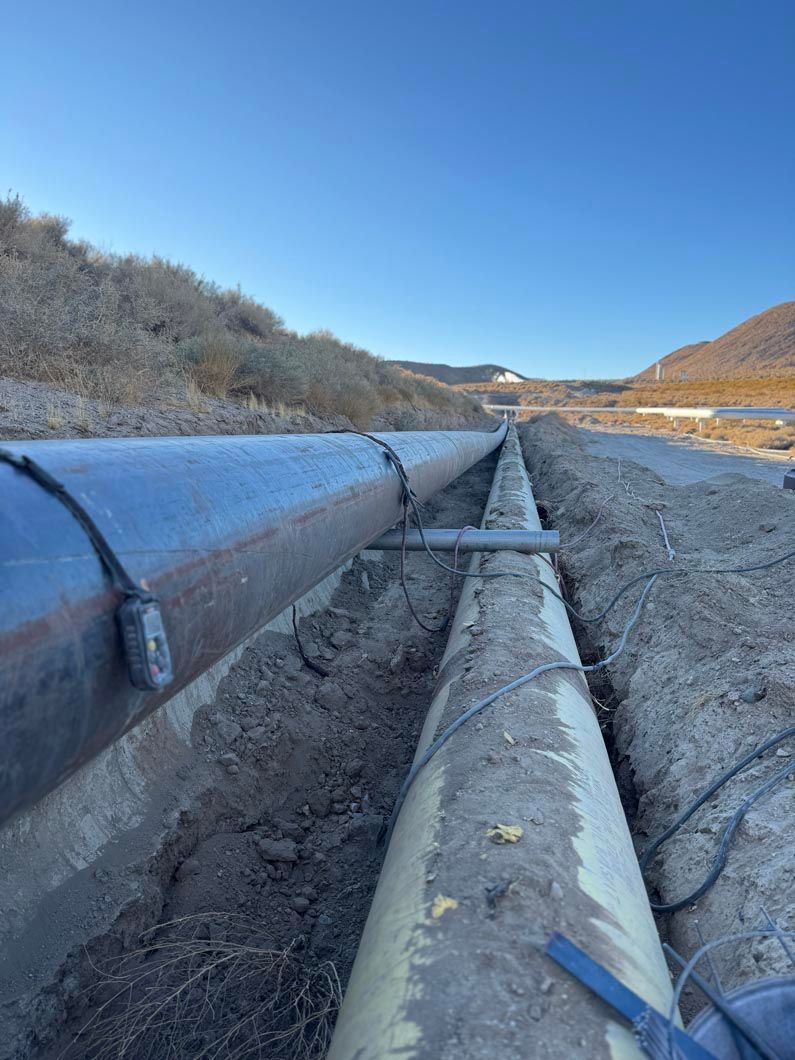 A couple of pipes are sitting in the dirt next to a road.