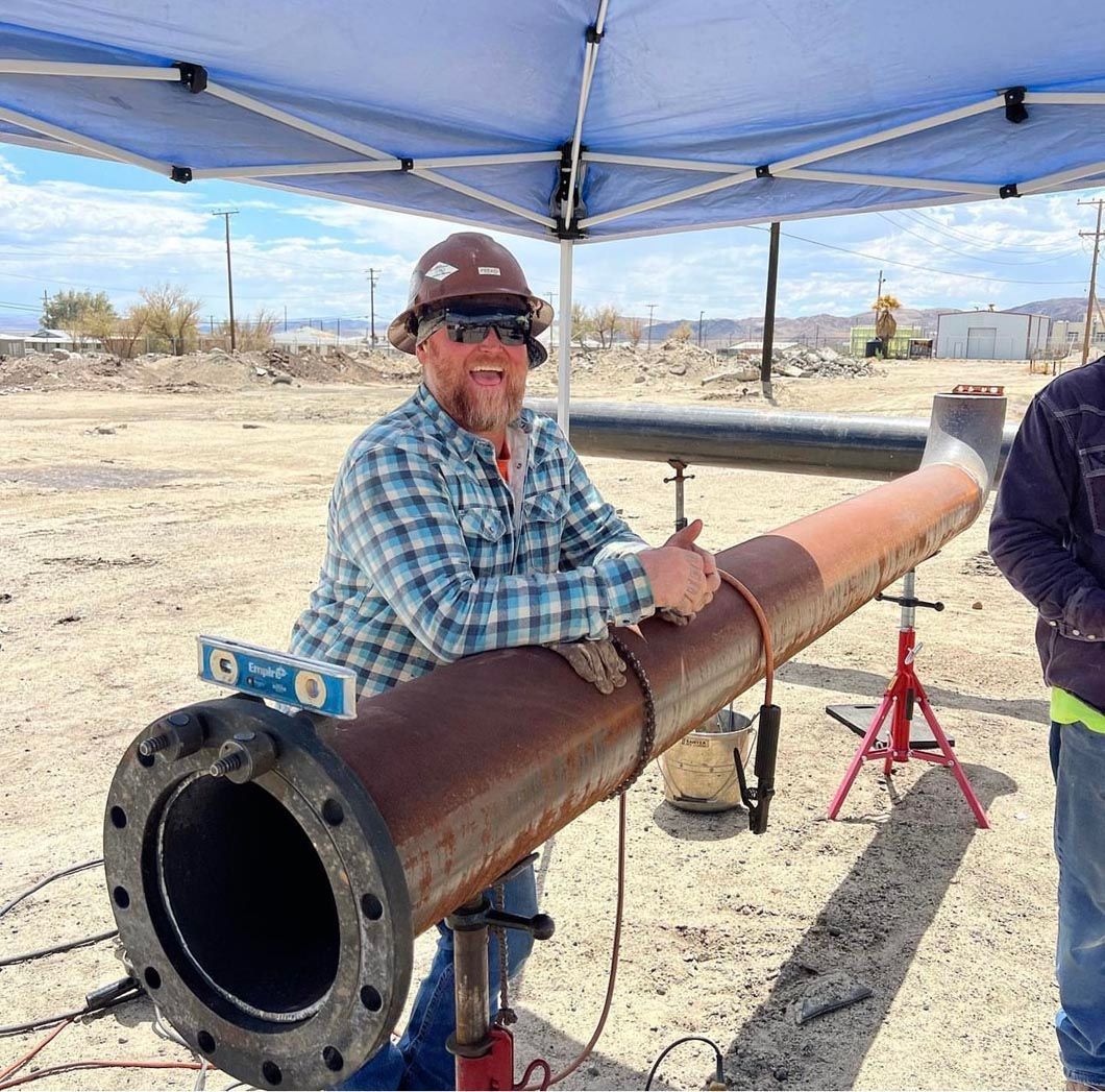 A man is standing next to a large pipe under a tent.