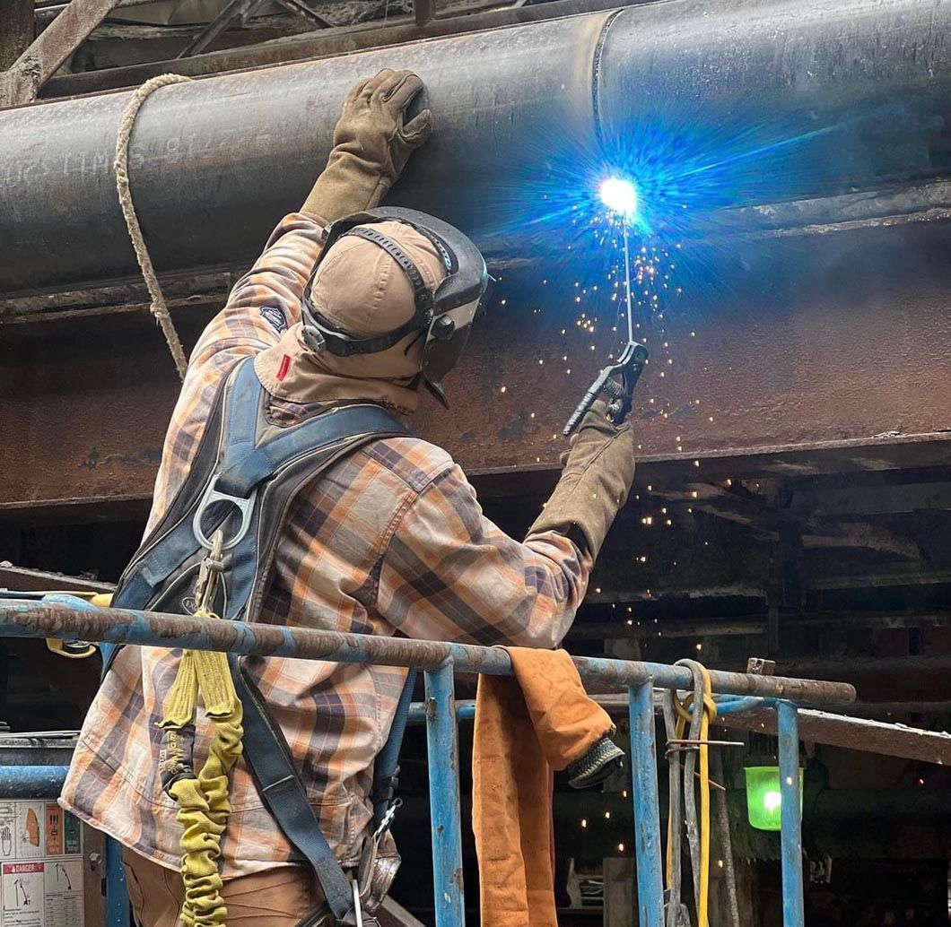 A man is welding a pipe with a torch.