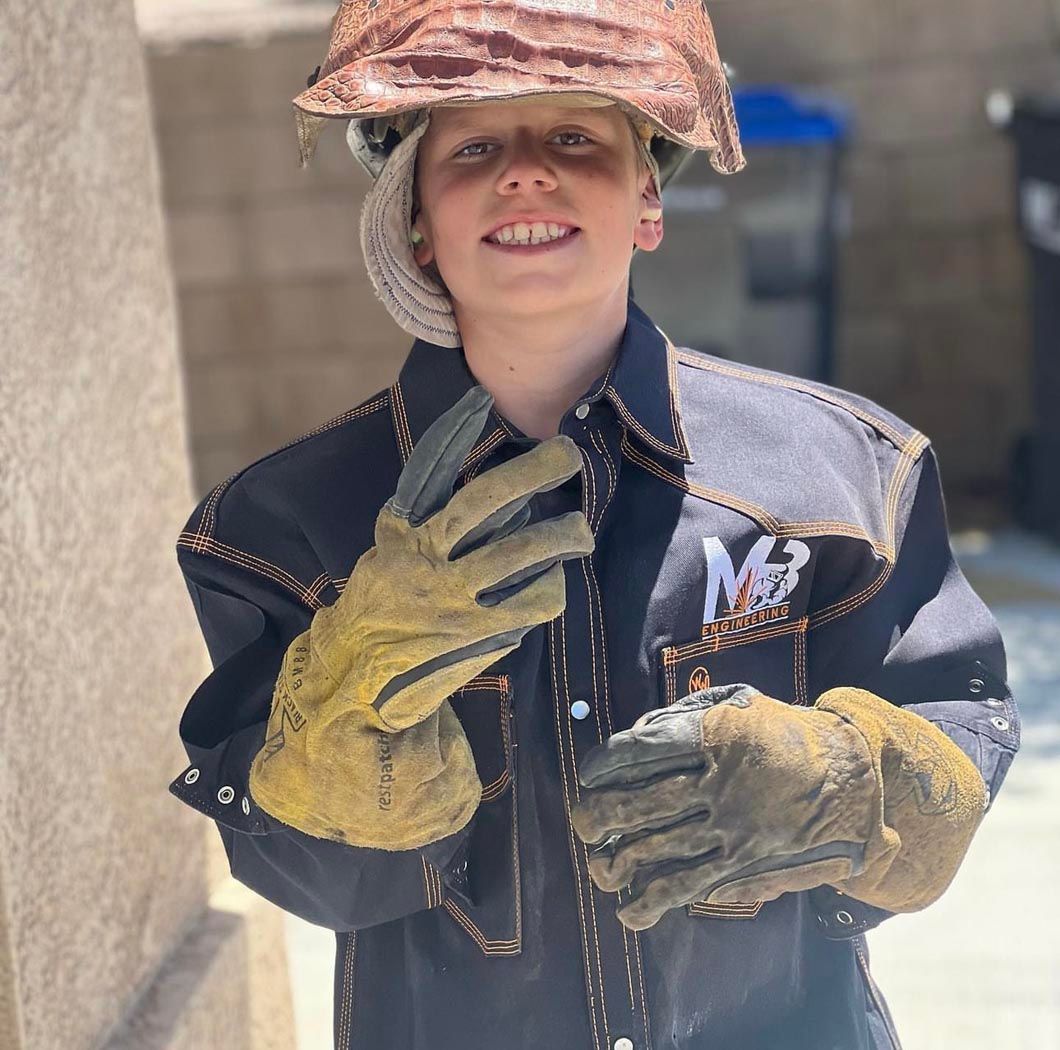 A young boy wearing a hard hat and gloves