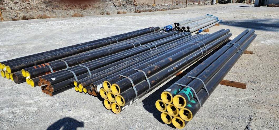 A bunch of metal pipes are stacked on top of each other on the ground.