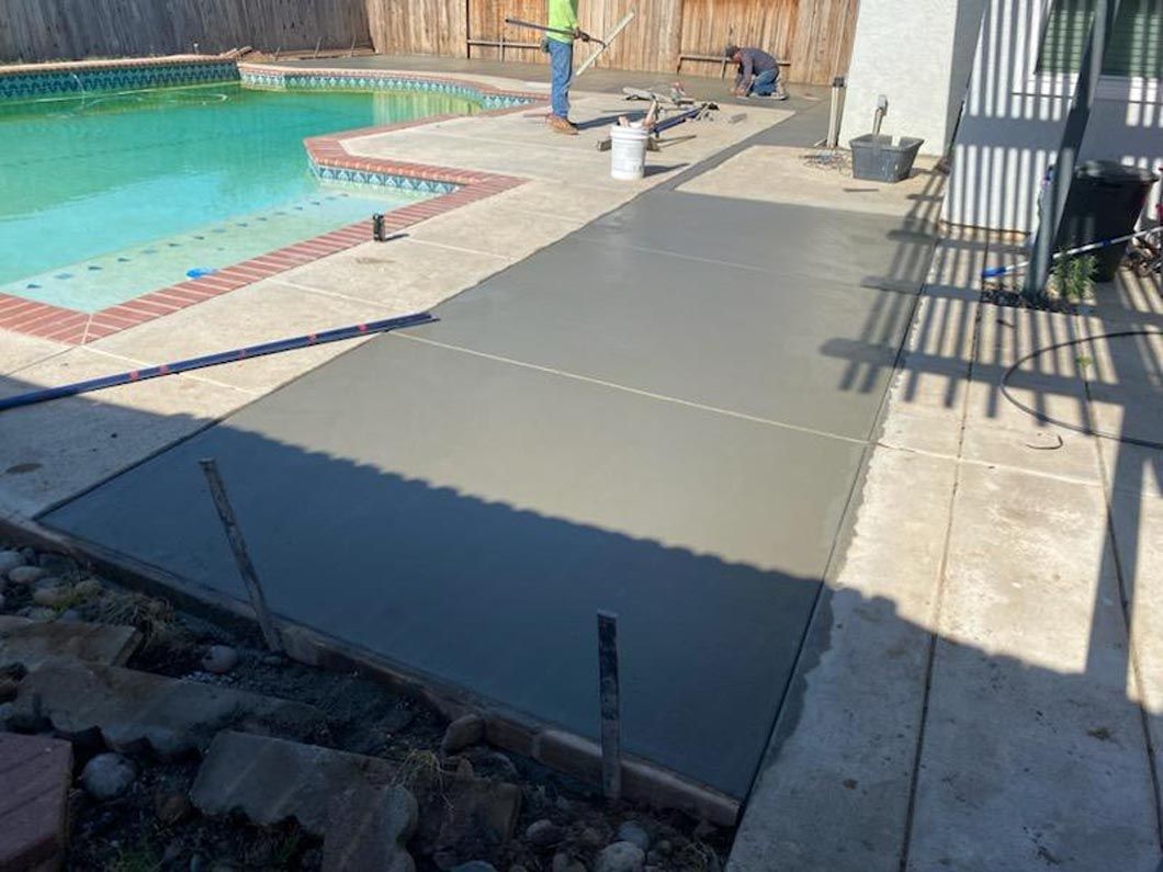 A concrete walkway is being built next to a swimming pool.