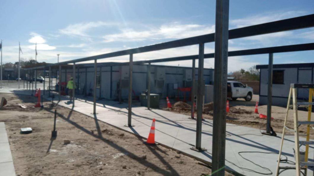 A large metal structure is being built in the middle of a dirt field.