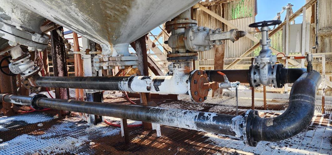 A bunch of pipes and valves are sitting on the ground in a factory.