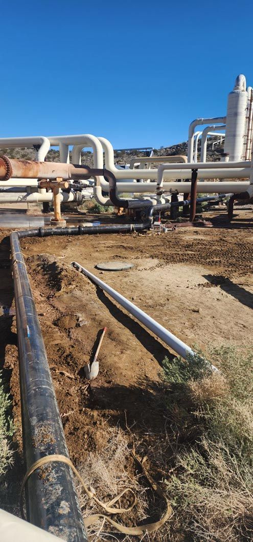 A bunch of pipes are laying in the dirt in a field.