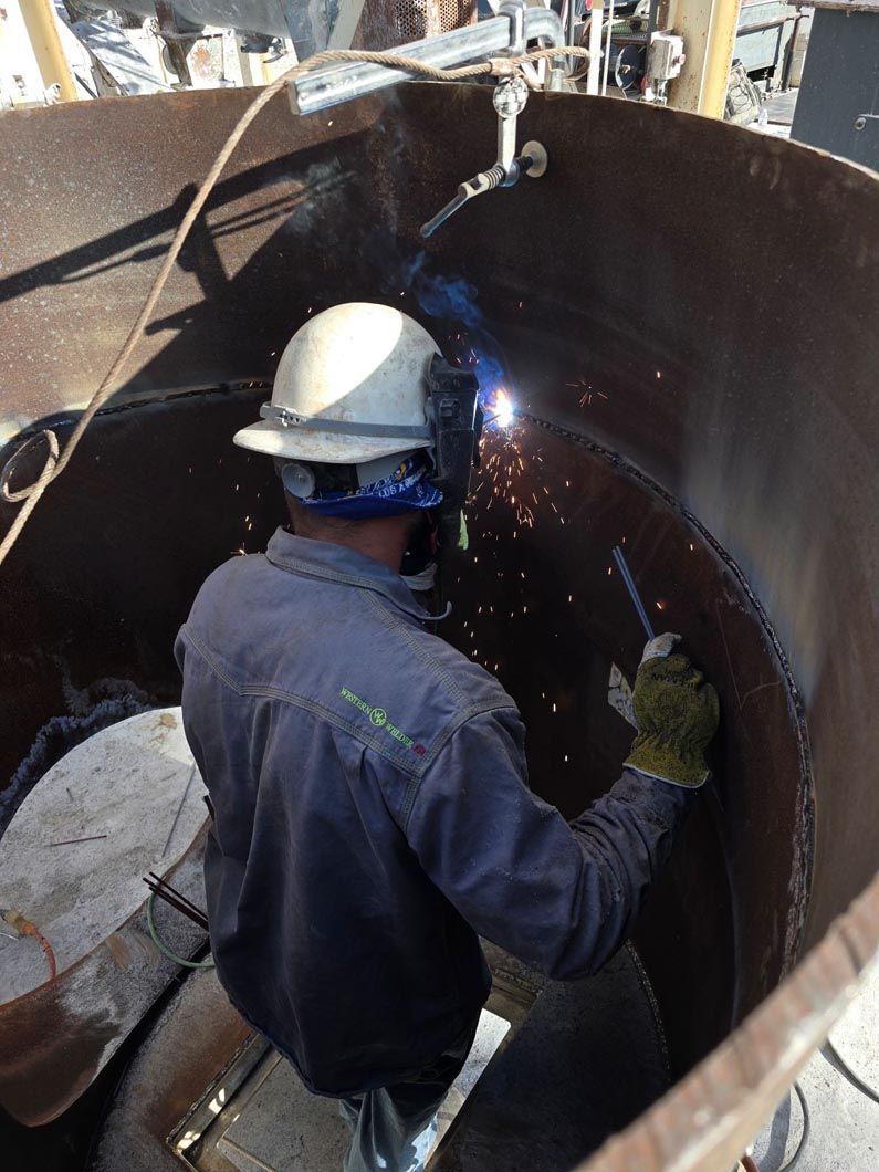 A man wearing a hard hat is welding a piece of metal.