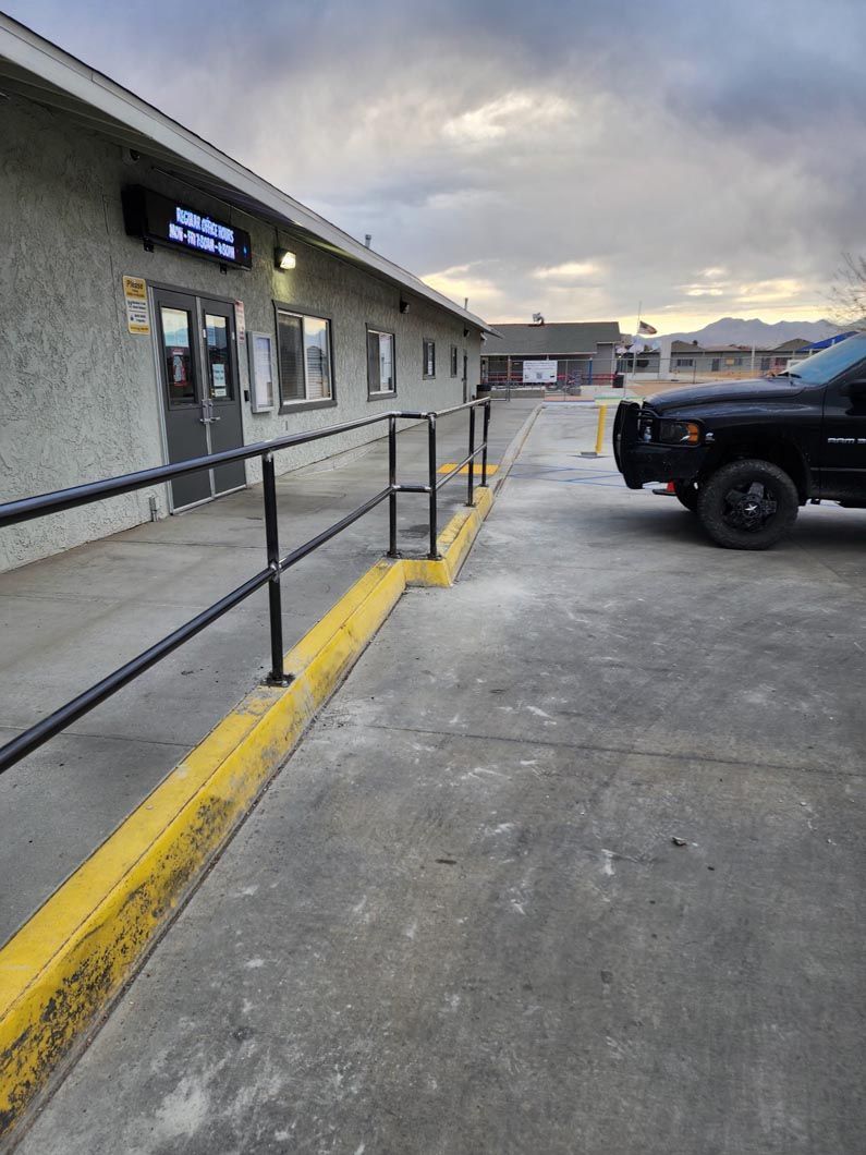 A black truck is parked in front of a building with a yellow curb.