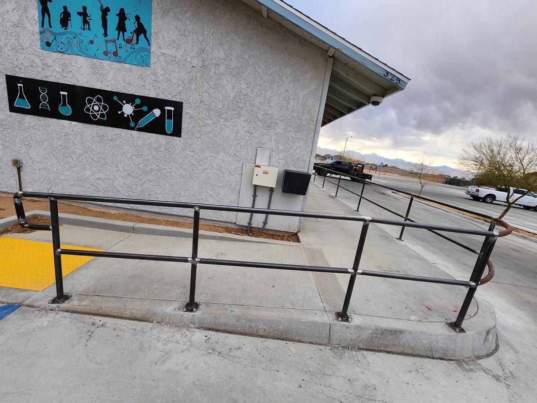 A concrete ramp with a metal railing leading to a building