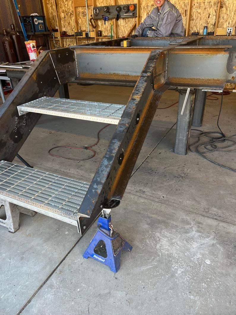 A man is working on a metal staircase in a garage.