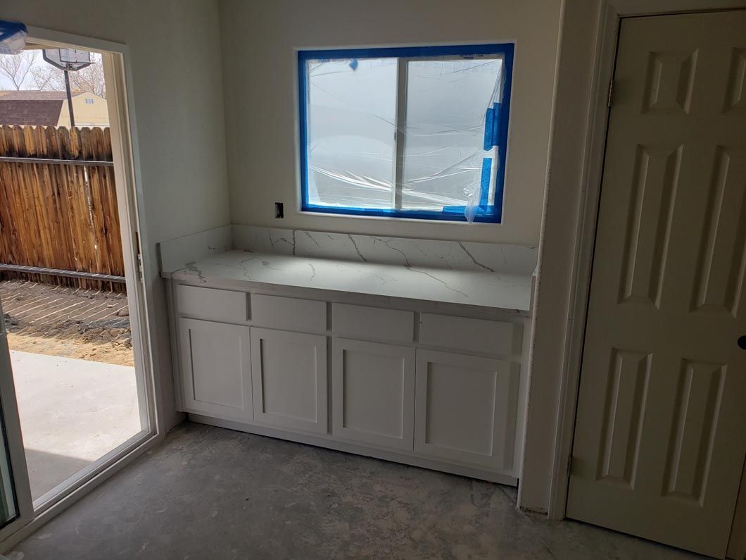 A kitchen with white cabinets and a window with blue tape on it.