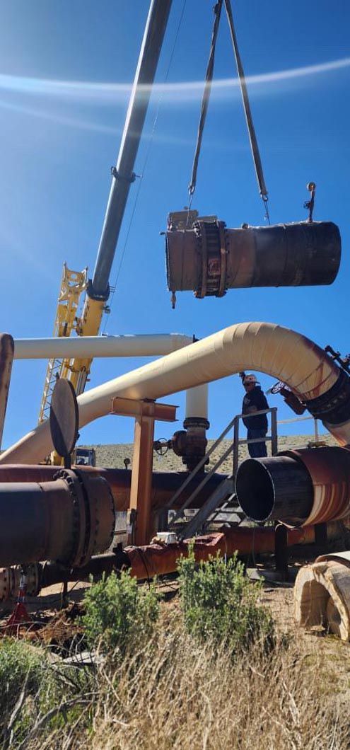 A large pipe is being lifted by a crane.