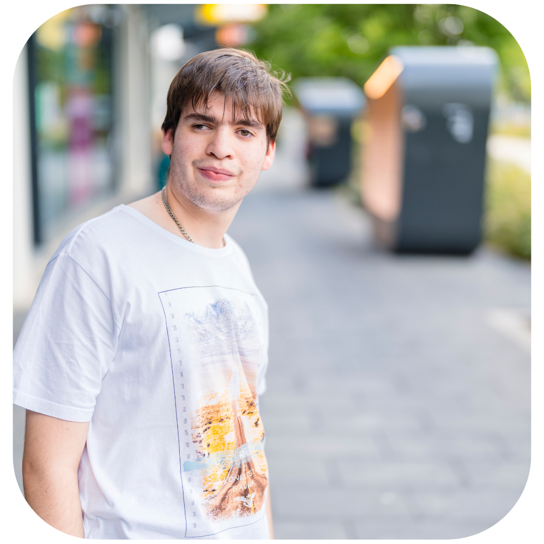 Young man standing outside, looking at the camera.